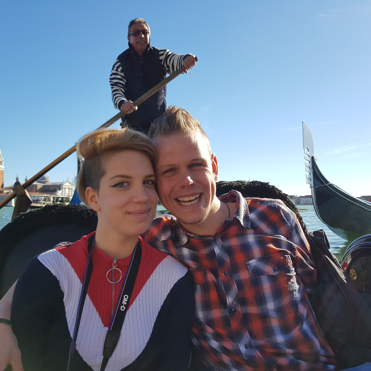 Olli und Julia von Hadscho Unterwegs lächelnd in einer Gondel auf dem Canal Grande in Venedig, Italien, mit Gondoliere im Hintergrund