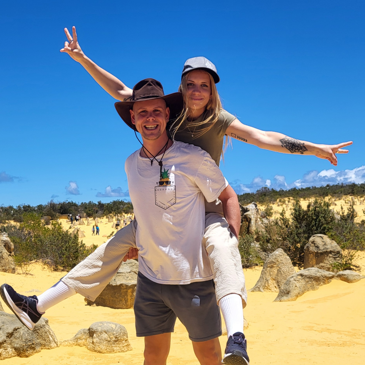 Olli und Julia von Hadscho Unterwegs in der Pinnacle Desert in Westaustralien, Australien, lachend vor den charakteristischen Kalksteinsäulen des Nambung National Park